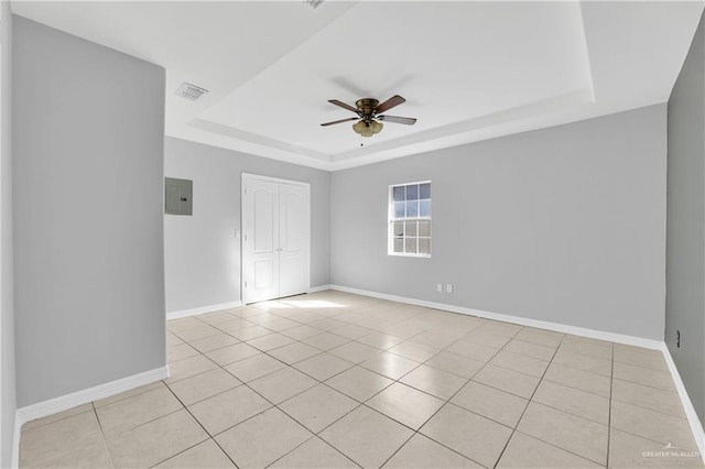 tiled spare room with ceiling fan, a raised ceiling, and electric panel