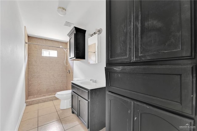 bathroom with tile patterned floors, vanity, tiled shower, and toilet