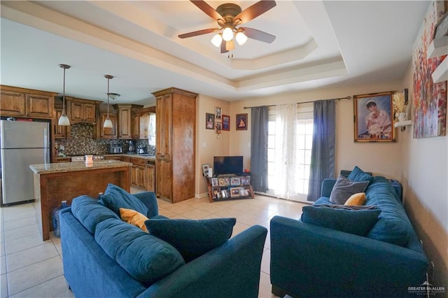 tiled living room featuring ceiling fan and a tray ceiling