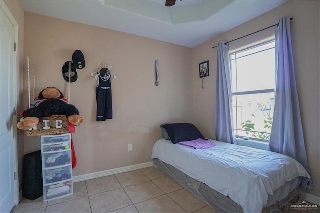 bedroom with ceiling fan, light tile patterned floors, and a tray ceiling