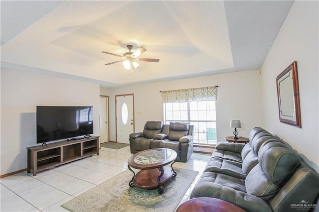 tiled living room featuring a raised ceiling and ceiling fan