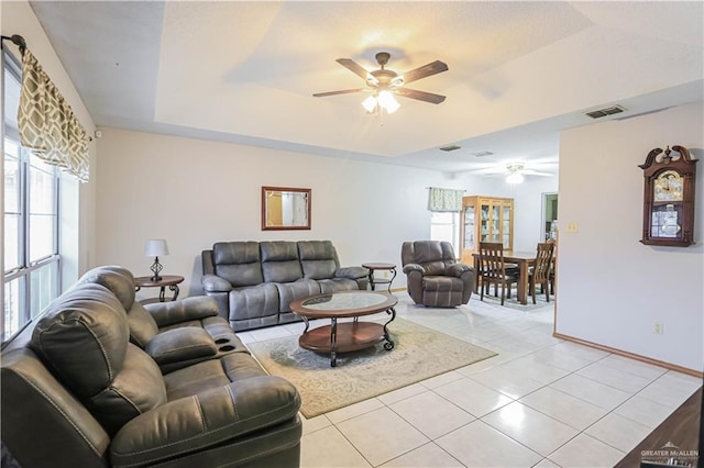 tiled living room with a raised ceiling and ceiling fan