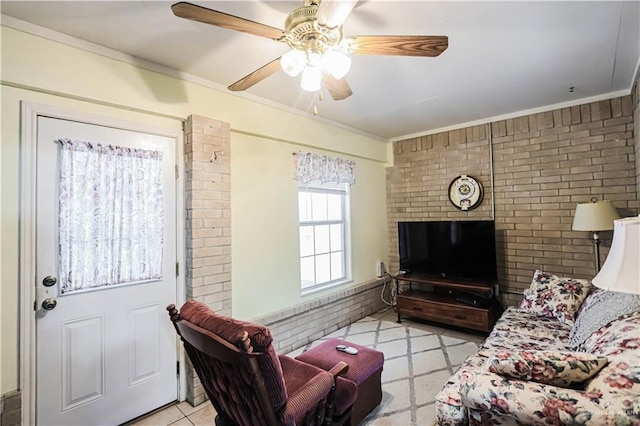 living room with ceiling fan, ornamental molding, and brick wall