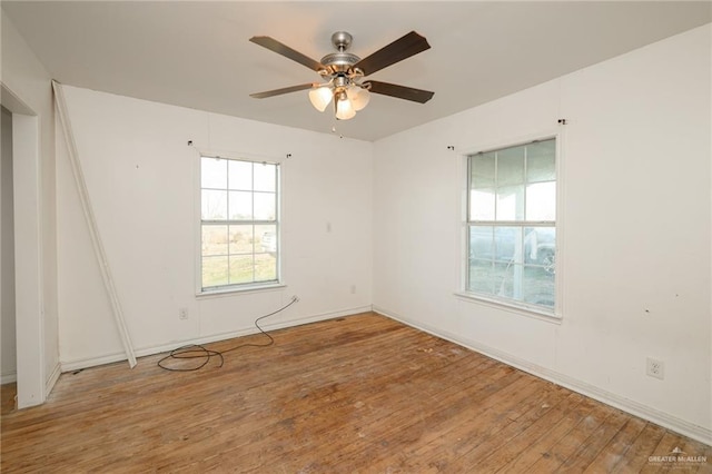 empty room featuring baseboards, hardwood / wood-style flooring, and a ceiling fan