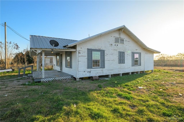 back of house featuring metal roof and a yard