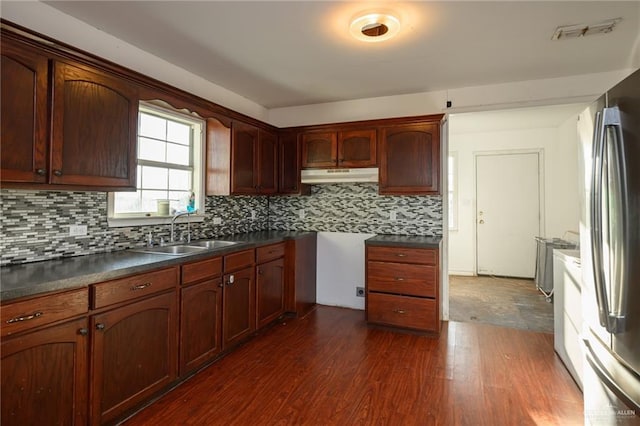 kitchen with visible vents, dark wood-type flooring, freestanding refrigerator, a sink, and under cabinet range hood