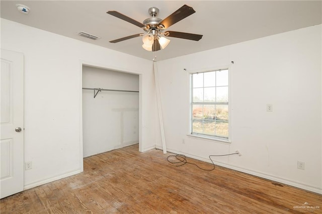 unfurnished bedroom featuring a ceiling fan, a closet, visible vents, and wood finished floors