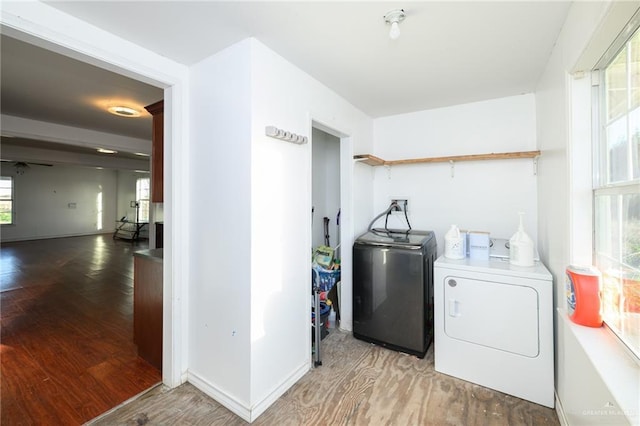 washroom with washing machine and dryer, laundry area, light wood-style flooring, and baseboards