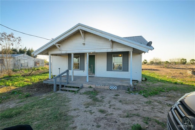 bungalow-style home with covered porch and metal roof