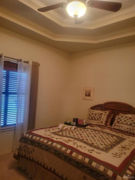 carpeted bedroom featuring crown molding, ceiling fan, and a raised ceiling