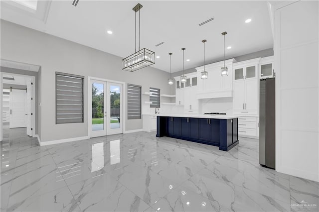 kitchen featuring a spacious island, hanging light fixtures, stainless steel refrigerator, white cabinets, and french doors