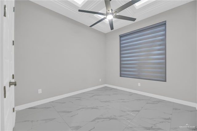 empty room featuring ceiling fan, a skylight, and ornamental molding