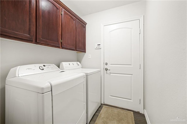 laundry room with dark wood-type flooring, washing machine and dryer, cabinet space, and baseboards