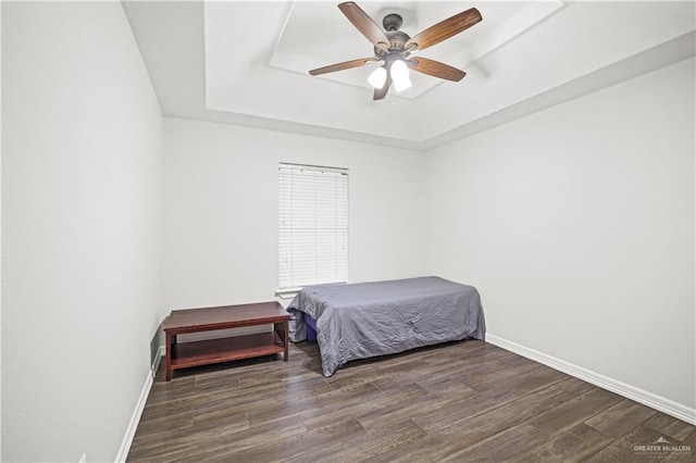 bedroom featuring a raised ceiling, baseboards, and wood finished floors