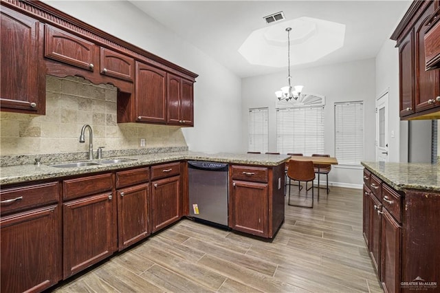 kitchen with a tray ceiling, visible vents, a sink, dishwasher, and a peninsula