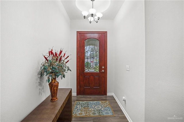 doorway to outside featuring baseboards, dark wood finished floors, and a notable chandelier