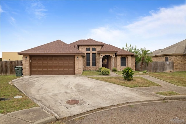 view of front of home featuring concrete driveway, an attached garage, fence, a front yard, and brick siding