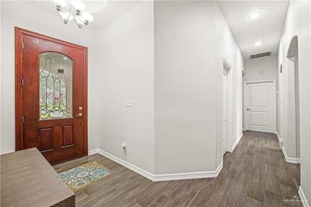 foyer entrance featuring visible vents, baseboards, dark wood finished floors, and a chandelier