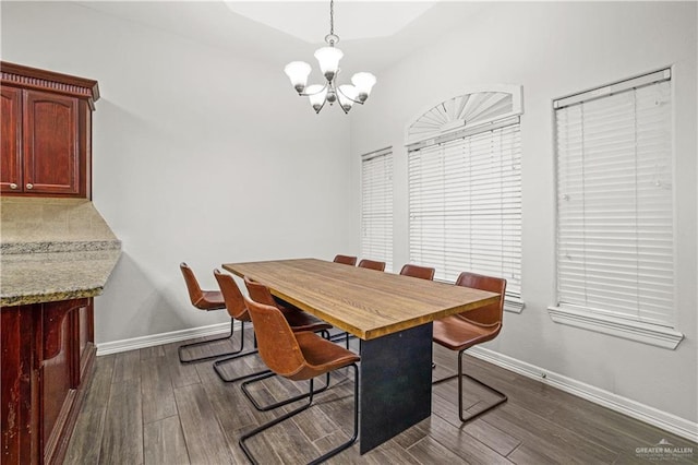 dining area with dark wood-type flooring, baseboards, and an inviting chandelier