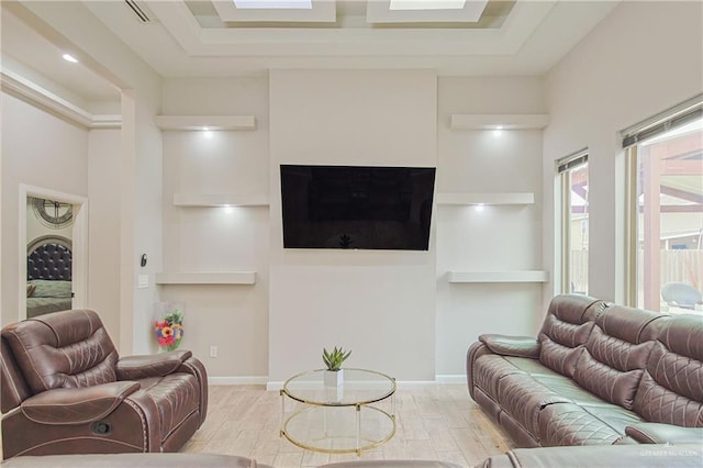 living area with visible vents, baseboards, a raised ceiling, and wood finished floors