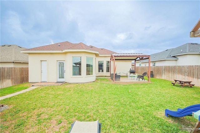 back of house featuring a yard, a patio area, a fenced backyard, and stucco siding