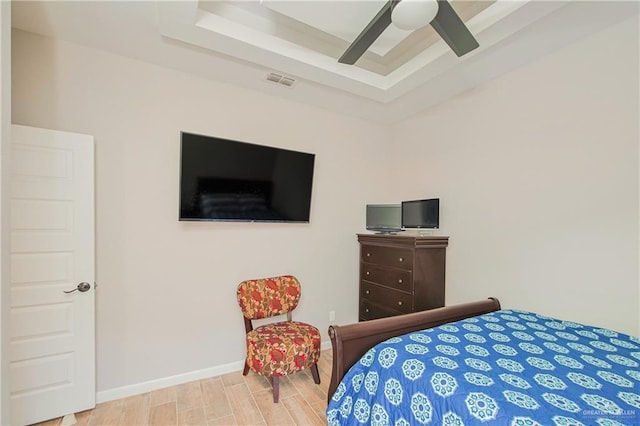 bedroom featuring visible vents, wood tiled floor, a tray ceiling, and baseboards