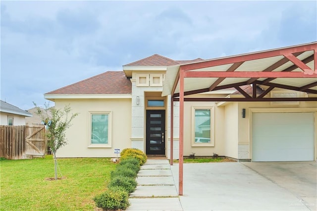 view of front of house with a garage, concrete driveway, fence, a front lawn, and stucco siding