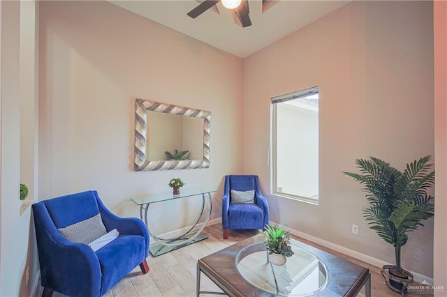 living area featuring wood finished floors, a ceiling fan, and baseboards