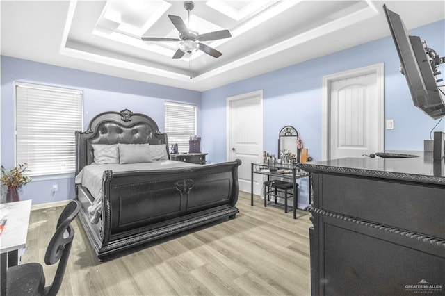 bedroom featuring a raised ceiling, ceiling fan, and light wood-type flooring