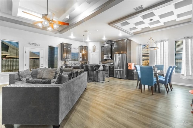 living room with hardwood / wood-style flooring, ceiling fan, and a tray ceiling