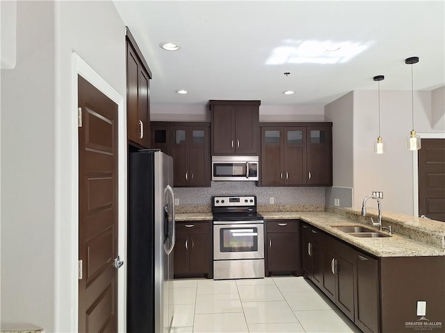 kitchen featuring backsplash, hanging light fixtures, sink, appliances with stainless steel finishes, and kitchen peninsula