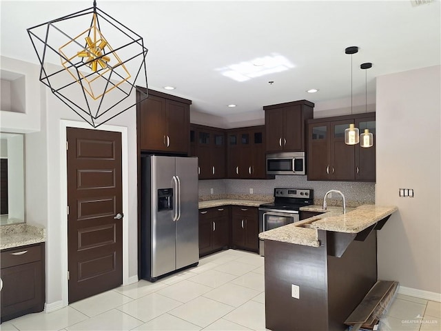 kitchen featuring stainless steel appliances, tasteful backsplash, kitchen peninsula, pendant lighting, and dark brown cabinets