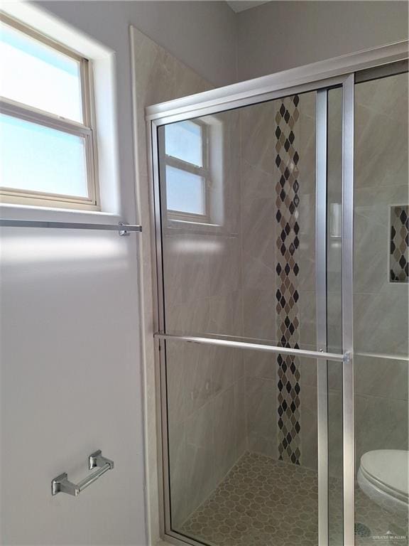 bathroom with toilet and a shower with shower door