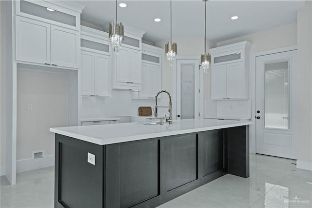 kitchen with pendant lighting, white cabinetry, a kitchen island with sink, and sink