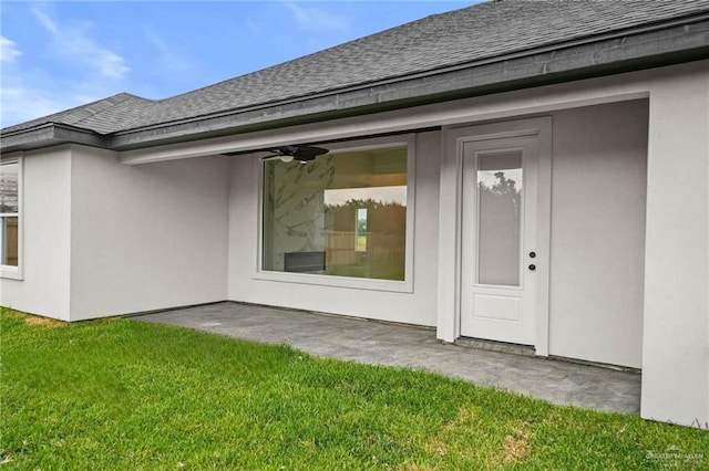 view of exterior entry featuring a patio, ceiling fan, and a lawn