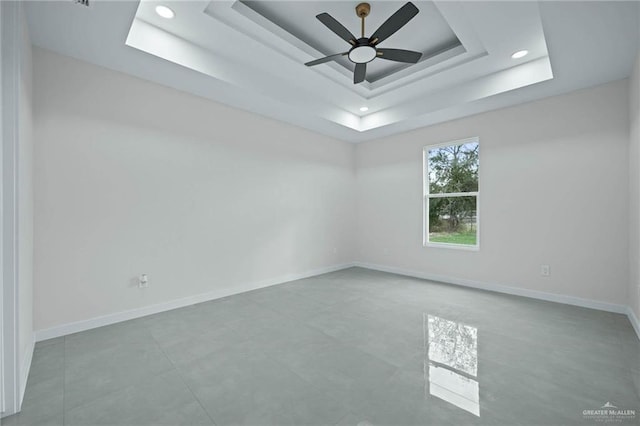 unfurnished room featuring a raised ceiling and ceiling fan