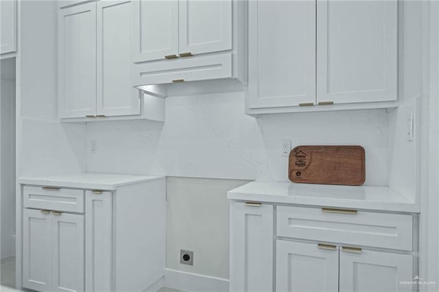 interior space with white cabinets, backsplash, and light stone countertops