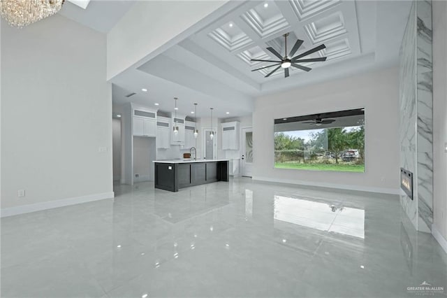 unfurnished living room featuring ceiling fan with notable chandelier and sink