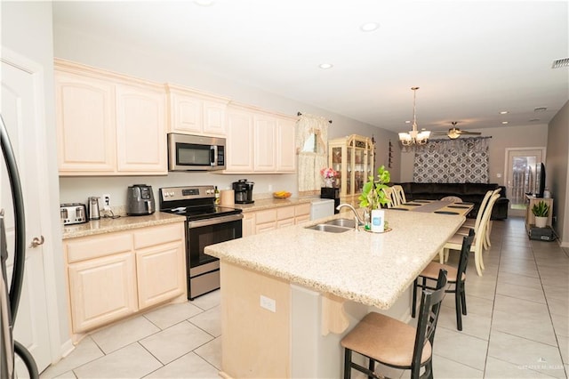 kitchen featuring a kitchen island with sink, a sink, a kitchen breakfast bar, open floor plan, and appliances with stainless steel finishes