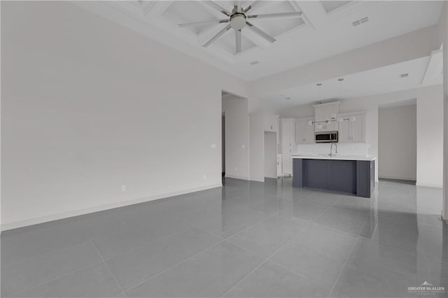 unfurnished living room featuring light tile patterned floors, coffered ceiling, and beamed ceiling