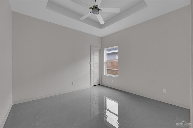 empty room featuring ceiling fan and a tray ceiling