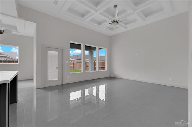 unfurnished living room with ceiling fan, tile patterned flooring, beamed ceiling, and coffered ceiling