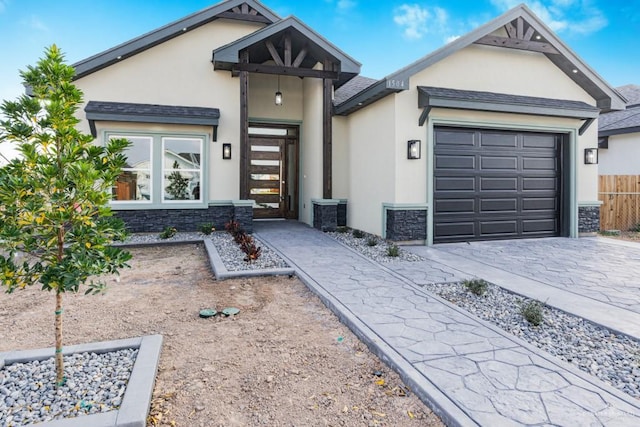 view of front of house featuring central AC unit, a garage, stone siding, decorative driveway, and stucco siding