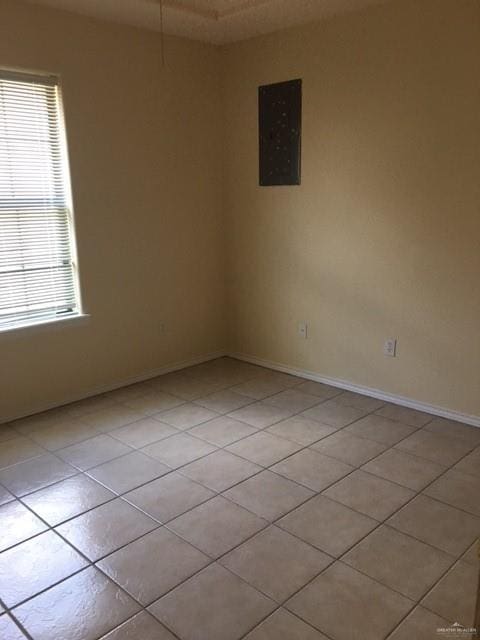 spare room featuring light tile patterned flooring, baseboards, and electric panel