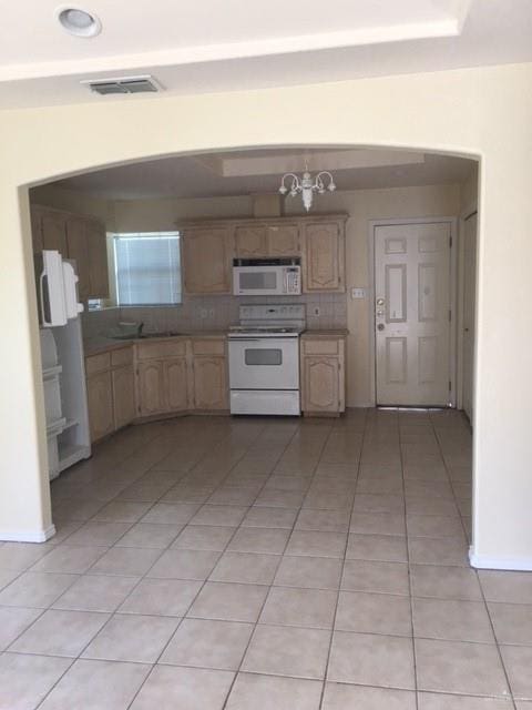 kitchen featuring light tile patterned flooring, backsplash, a chandelier, white appliances, and visible vents