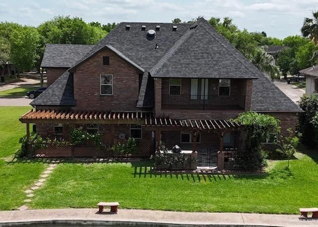 109 Palm Valley Cir, Harlingen, TX 78552 - rear view of house featuring a patio, roof with shingles, a balcony, and a lawn