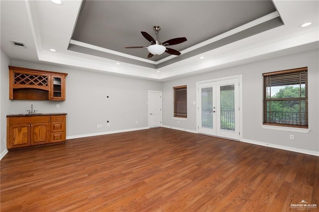 109 Palm Valley Cir, Harlingen, TX 78552 - unfurnished living room featuring ceiling fan, wet bar, french doors, crown molding, and a tray ceiling