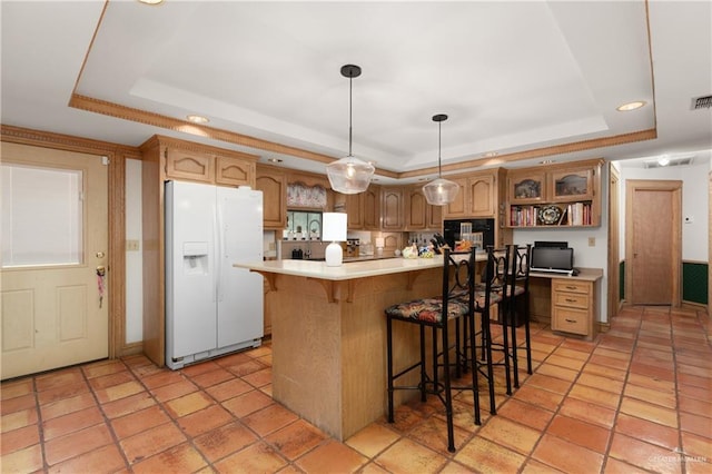 kitchen with a breakfast bar, a tray ceiling, white refrigerator with ice dispenser, pendant lighting, and a kitchen island