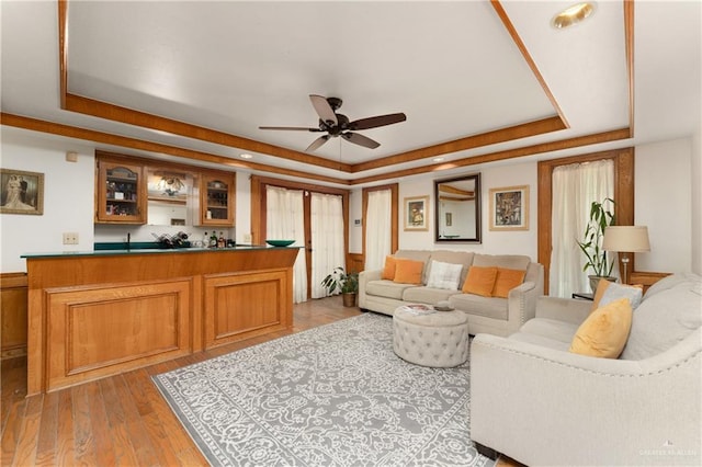 living room featuring a raised ceiling, bar, ceiling fan, and light hardwood / wood-style flooring