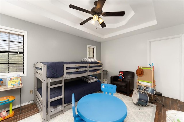 bedroom featuring a raised ceiling, ceiling fan, and dark wood-type flooring